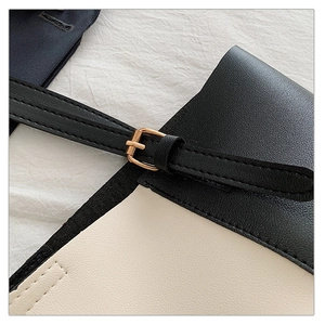 Close-up of contrast tote bag showing fine leather texture and golden metal buckle