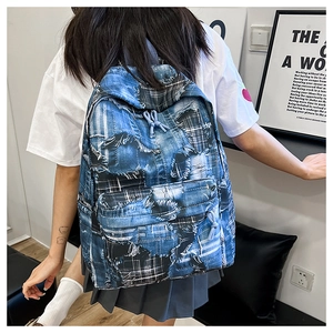 Close-up of blue denim backpack showing distressed texture and checkered patchwork detail