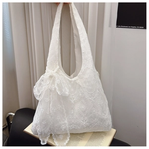 Detail of white lace embroidery tote bag featuring floral patterns and a 3D lace bow