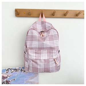Close-up of pink checkered backpack with multiple pockets hanging on a wooden hook