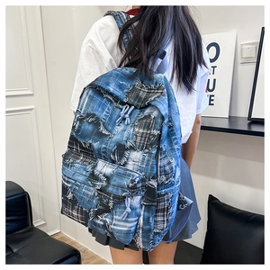 Detail of blue denim patchwork backpack with distressed edges and drawstring zippers