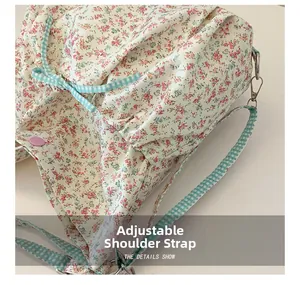 Detail of floral canvas tote showing adjustable blue checkered strap and metal D-ring