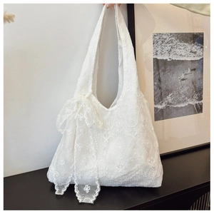 Close-up of white lace floral embroidery and bow detail on a canvas tote bag