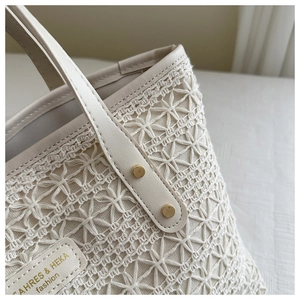 Detailed macro view of cream woven tote bag with PU leather trim and gold rivet accents