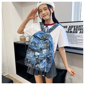 Detailed view of the patchwork denim backpack with graffiti print and plaid elements