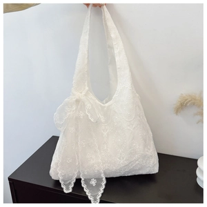 Detailed view of floral lace embroidery and a delicate bow on this white canvas tote bag