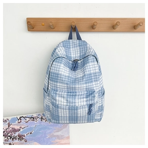 Detailed view of a blue and white checkered canvas backpack hanging on a wooden wall hook
