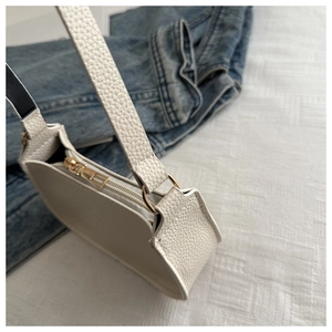 Detailansicht der weißen Achseltasche mit Lychee-Muster und goldenen Metall-Reißverschluss