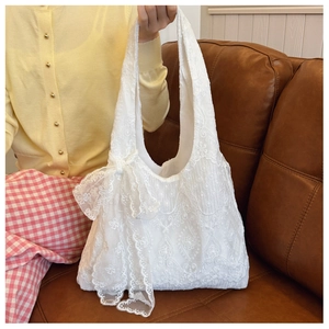 Close-up of white floral lace tote bag featuring a large decorative side bow detail