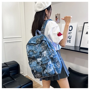 Detail of frayed denim patchwork backpack with plaid accents and drawstring on model