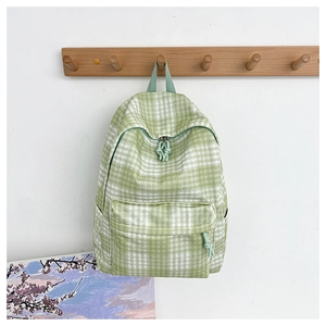Detail of green and white gingham backpack with woven rope zipper pulls on a wall hook