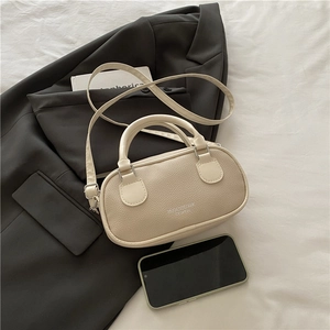 Minimalist cream litchi leather bowling bag with top handles and adjustable strap