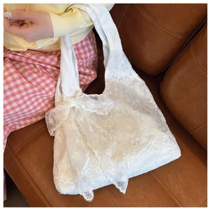 Detail shot of white crochet lace tote bag featuring a large decorative bow detail