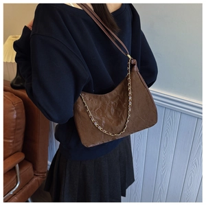 Detail view of a dark brown pleated tote bag with fine straps and gold chain accents