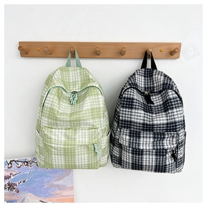 Detail of minimalist green and black checkered backpacks hanging on a wooden rack