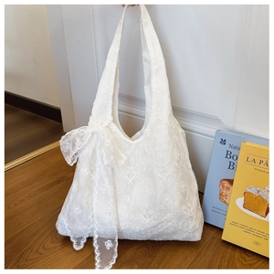 Detail of white lace tote bag with oversized decorative bow and floral texture