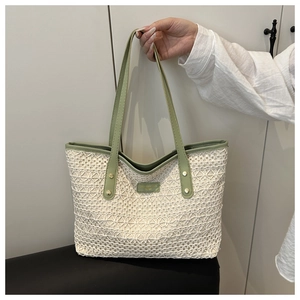 Close-up of beige crochet tote bag with sage green leather trim and rivet details