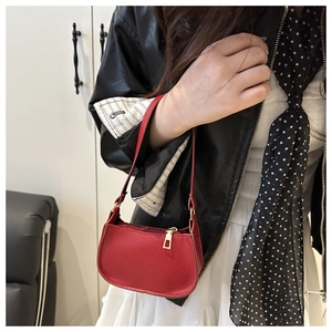 Detail of red crescent bag with lychee leather texture and gold zipper on leather jacket