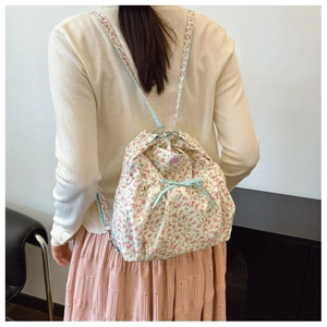 Floral drawstring canvas backpack with bow detail and floral pattern shown on model