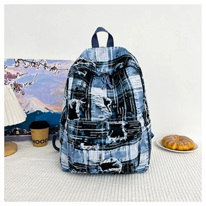 Detailed view of blue and white denim backpack featuring aesthetic patchwork and frayed edges
