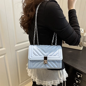 Chic light blue chevron quilted crossbody bag with silver chain strap worn by a model