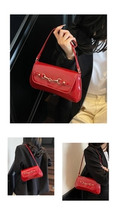 Détail du sac baguette en cuir verni rouge avec boucle équestre dorée et fine bandoulière