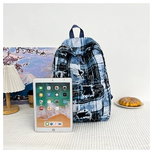 Detail of blue patchwork backpack with frayed edges shown next to a tablet and coffee