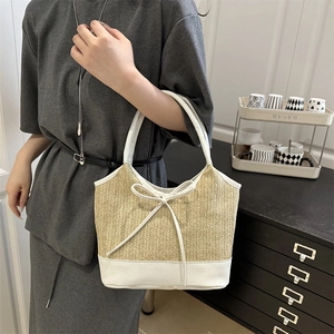 Large hand-woven beige straw shoulder bag with white leather trim and ribbon bow