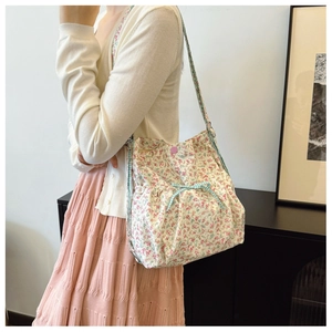 Floral canvas shoulder bag with green checkered bow detail shown on a model side view