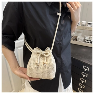 Detailaufnahme der beigen gewebten Beuteltasche mit Kordelzug und eleganten Goldperlen
