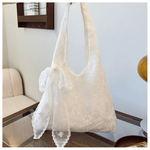 Detail of white lace flower embroidery and large side bow on canvas shoulder bag