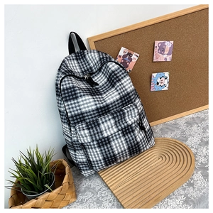 Detail view of a black and white checkerboard backpack with front zipper and durable fabric