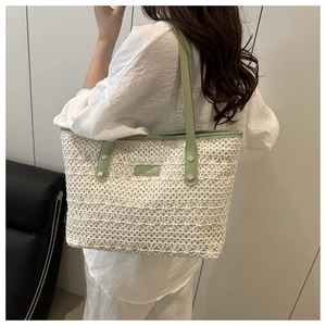 Detail of woven lace tote bag with sage green leather straps and metallic fashion logo