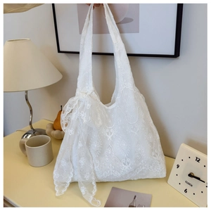 Detailed close-up of delicate floral lace embroidery and soft ribbon bow on white tote bag