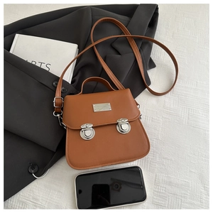 Detail of vintage brown bucket bag with dual silver buckles and size comparison with phone