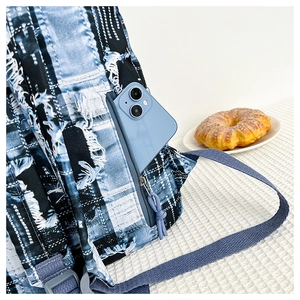Detail showing the side zipper pocket of blue tie-dye backpack with a smartphone inside