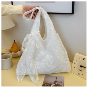 Detail of white lace tote bag featuring floral embroidery and a large decorative bow