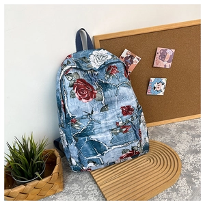 Detailed close-up of blue floral backpack with red and white rose prints and front pocket