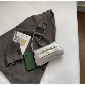 Détail du sac baguette argenté avec boucle mors dorée et texture cuir plissé chic