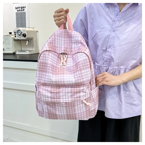 Detailed shot of pink and white plaid canvas backpack with front zipper pocket and cords