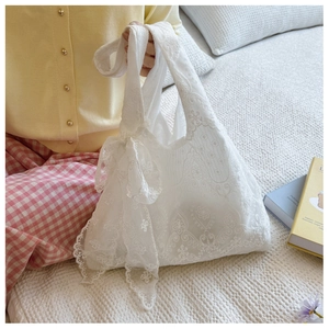 Close-up of white lace tote bag with floral embroidery and elegant bow detail