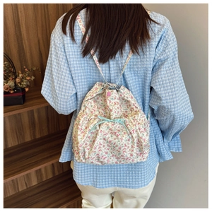 Detail of floral canvas backpack featuring a blue plaid bow and pink snap button closure