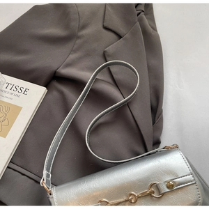 Détail du sac bandoulière argenté brillant avec mors métallique et texture plissée