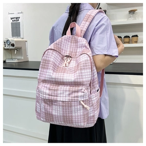 Detail of pink plaid canvas backpack featuring adjustable straps and a side pocket