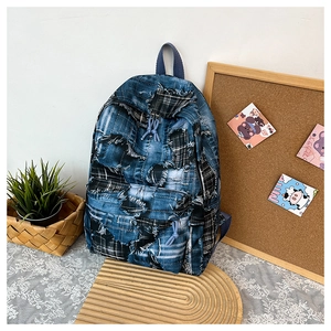 Detail of patchwork denim backpack with frayed edges and blue plaid on lace tablecloth