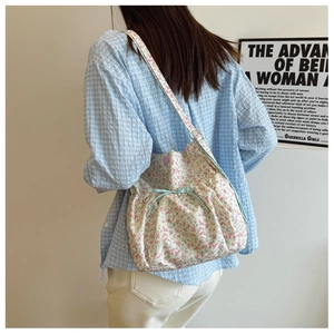 Floral print fabric shoulder bag with a checkered bow detail shown on a model