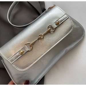 Détail macro d'un sac à bandoulière argenté avec boucle mors en métal doré vintage