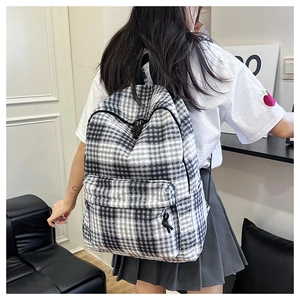 Close-up of stylish black and white checkered canvas backpack on model showing back view
