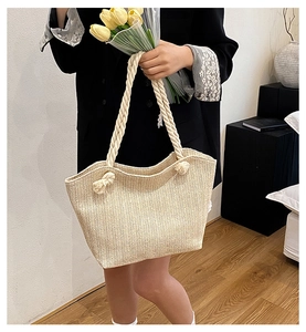 Detail of hand-woven beige straw tote bag with sturdy cotton rope handles in home setting