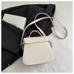 Detail of minimalist off-white PU leather bucket bag with silver hardware and thin strap